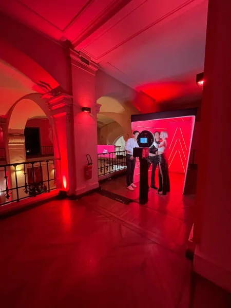 Photobooth et photocall Catchingbox illuminés de néons rouges, capturant des invités lors d'un événement élégant.